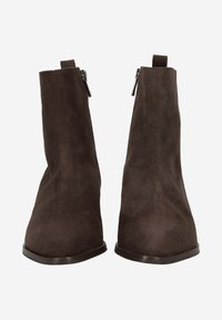 Bottines en daim marron avec une texture lisse, dotées d'une fermeture éclair sur le côté externe et d'un petit talon arrondi.