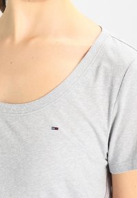 Gray cotton t-shirt featuring a round neckline and short sleeves, with a small embroidered logo detail on the chest.