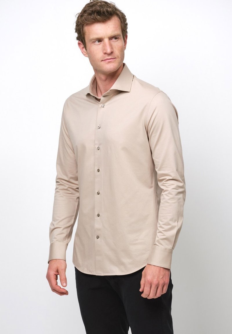 Beige langärmeliges Hemd mit Knöpfen und Kragen, aus glattem Stoff gefertigt, der leicht schimmert, mit kontrastierenden silbernen Knöpfen.
