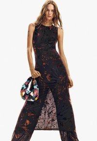 Czarna sukienka w kwiaty o dopasowanym kroju z bocznym rozcięciem. Do kompletu kolorowa torebka o fakturze, z zaokrąglonym uchwytem.