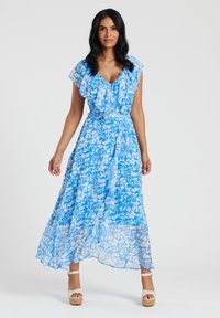Niebieska maxi sukienka w kwiaty z falbaniastymi rękawami, przezroczystym materiałem i dopasowaną talią. Warstwowa konstrukcja podkreśla płynność i ruch.