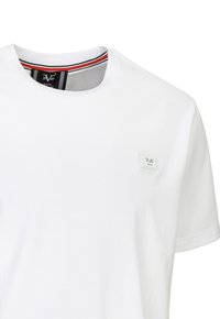 Weißes Baumwoll-T-Shirt mit rundem Halsausschnitt, das ein kleines Etikett auf der Brust und einen gestreiften Besatz im Kragen hat.