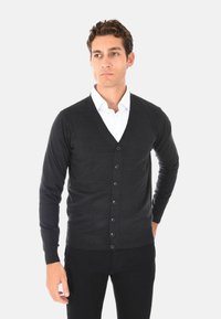 Cardigan nero a maniche lunghe realizzato in un materiale morbido, con scollo a V, chiusura frontale con sei bottoni e polsini e orlo a costine.