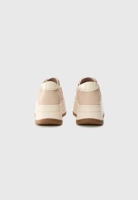 Baskets en cuir rose clair avec des accents beiges, dotées d'une semelle blanche épaisse et d'un design arrière arrondi pour un look moderne.