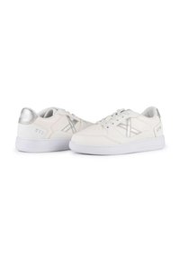 White sneakers with silver accents and textured leather. Features lace-up design, rubber sole, and logo detail on heel.