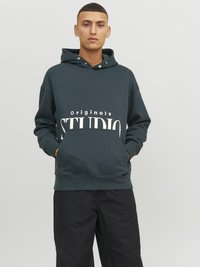 Mørkegrøn hoodie lavet af blødt stof, med en frontlomme, snørehætte og stort "STUDIO"-tekst i hvid.