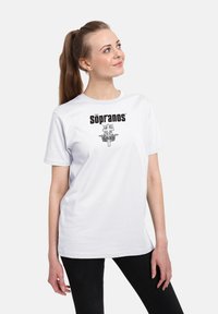 Hvid bomulds T-shirt med et sort "Sopranos" logo og et centralt grafisk design med et sværd og krone motiv. Korte ærmer, rund hals.
