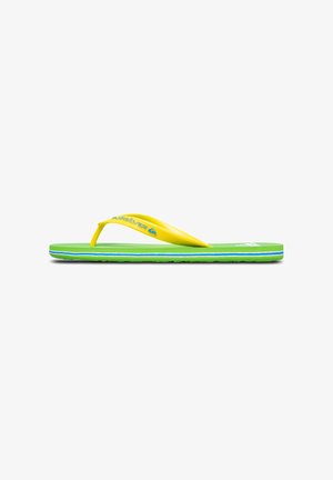 Geel rubberen flip-flop met een groene gestructureerde voetbed, met blauwe en witte strepen aan de zoolrand en een Quiksilver-logo op de strap.