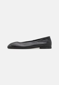 Ballerine en cuir noir avec un bout rond, texture lisse et semelle en caoutchouc basse. Design minimaliste sans matériel visible ni motifs.