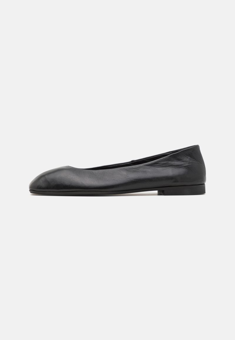 Ballerine en cuir noir avec un bout rond, texture lisse et semelle en caoutchouc basse. Design minimaliste sans matériel visible ni motifs.