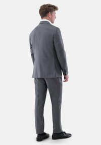 Grau Anzug mit strukturiertem Finish, taillierter Silhouette, zwei-Knopf-Verschluss, eingekerbten Revers und passenden Hosen. Schwarze Schuhe ergänzen das Outfit.