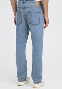 hele sinised teksad sirge säärega, millel on kaks tagataskut ja vöökohal helepruun nahast silt.