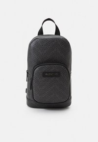 Svart Valentino-ryggsäck med upprepat logomönster, framficka med dragkedja, ögla upptill och justerbara band. Slätt syntetmaterial.