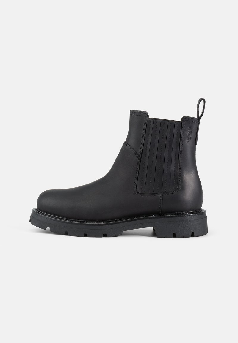 Botas Chelsea de cuero negro con paneles laterales elásticos, punta redonda, parte trasera texturizada y suela de goma gruesa con detalles de tracción.