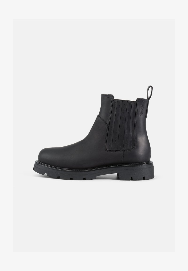 Botas Chelsea de cuero negro con paneles laterales elásticos, punta redonda, parte trasera texturizada y suela de goma gruesa con detalles de tracción.