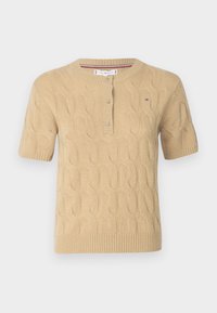 Pull en tricot beige à manches courtes avec un motif en torsades, col rond et une patte de boutonnage à trois boutons. Présente un petit logo sur la poitrine.