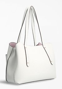 Sac cabas en cuir blanc texturé avec un design structuré, une bordure foncée contrastante et de longues poignées. L'intérieur est doublé de rose.