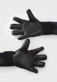 Svarta målvaktshandskar med texturerat grepp och avsmalnande fingrar. Vadderad handledsrem och slätt syntetmaterial.