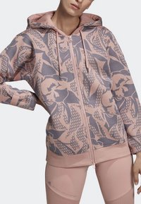 Růžová mikina na zip s květinovým vzorem v tmavších odstínech růžové, s klokánkovou kapsou a úpravami na kapuci a manžetách.