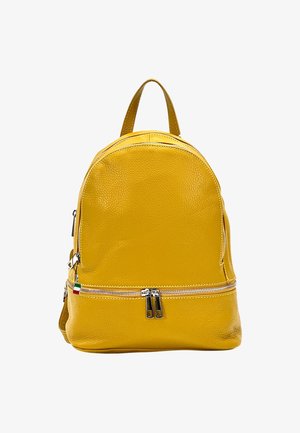 Geel leren rugzak met een ronde vorm, voorzien van twee ritssluitingen, een handvat aan de bovenkant en een kleine vlagaccent aan de zijkant.