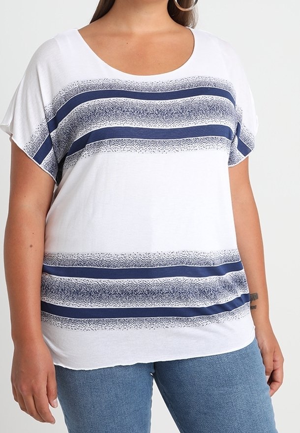 Top blanco de mangas cortas con rayas horizontales en color azul marino y texturas punteadas. Cuello redondeado, ajuste relajado, combinado con jeans de mezclilla.