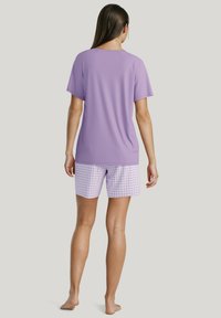 Lila korte mouwen top van zachte stof, gecombineerd met lavendel en witte ruitjes shorts met een elastische tailleband.