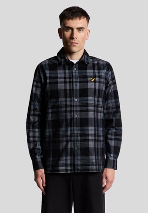 Sort og grå flannel skjorte med ternet mønster, knap-tryk design, kontrasterende blå og hvide detaljer, samt et lille gult logo på brystet.