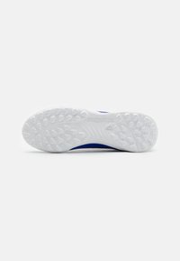 Semelle extérieure en caoutchouc blanc avec une adhérence texturée, et une partie supérieure bleue mettant en avant un design épuré et une texture lisse.