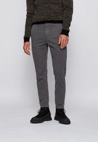 Grå bomullsbyxor med smal passform, utrustade med framfickor och en slät framdel, kombinerade med svarta snörskor.