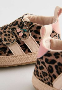 Leopardmönstrade sneakers med beige tyg, kardborreband, flätad jute-sula och rosa accenter nära hälen och bandet.