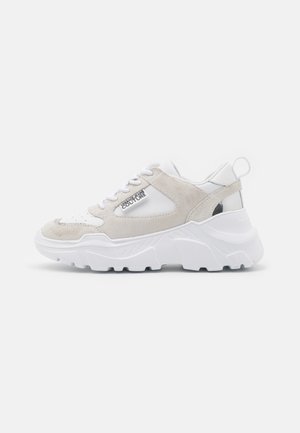 Witte en beige chunky sneaker met dikke zool en vetersluiting, voorzien van het "Versace Jeans Couture" logo op het zijpaneel.