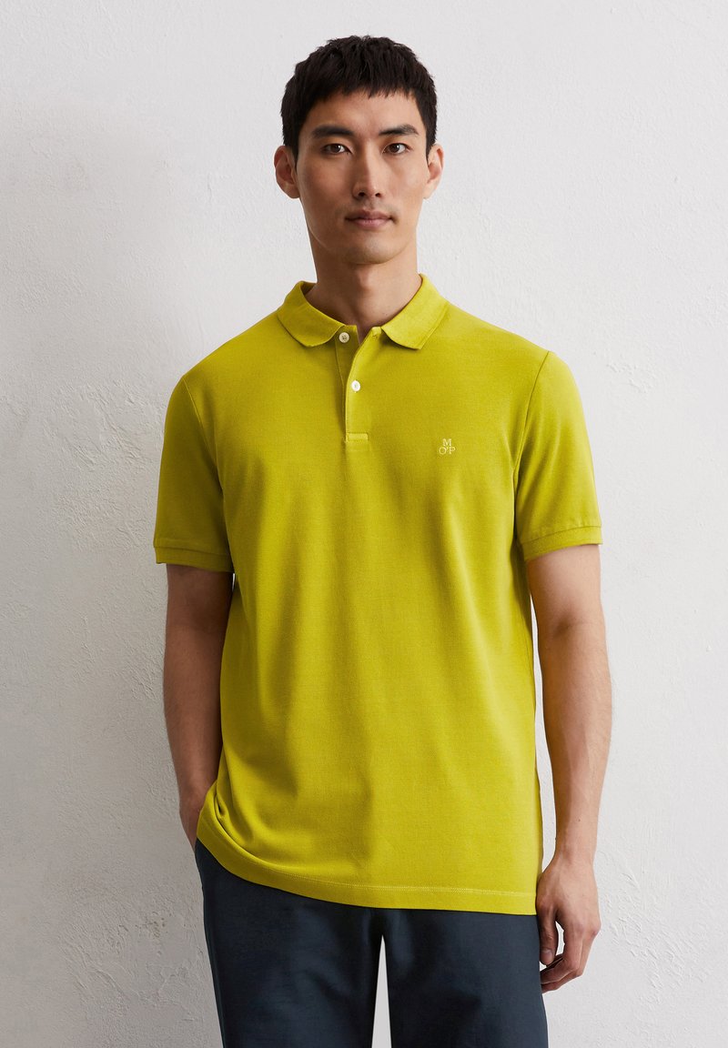 Limettengrünes Poloshirt aus weichem Material mit klassischem Kragen, kurzen Ärmeln und kleinem gesticktem Logo auf der linken Brust.