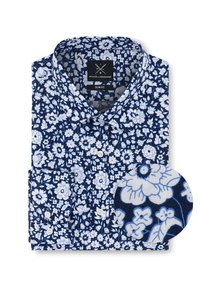 Granatowa koszula slim fit w biały kwiatowy wzór, z kołnierzykiem zapinanym na guziki i kieszonką na lewej piersi. Zbliżenie ukazuje fakturę tkaniny i szczegóły wzoru.