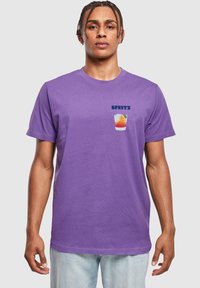 Camiseta de algodón morada con mangas cortas, que presenta el texto "SPRITZ" y un gráfico de un vaso colorido con una rodaja de naranja en el pecho.