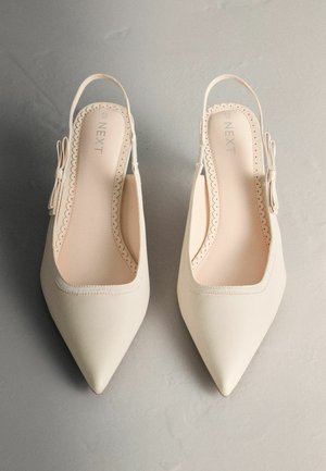 Teravnina talla ja kanna vabad kingad heledas valges materjalis, millel on lainelised servad ja dekoratiivne pael. Sile sisevooder.