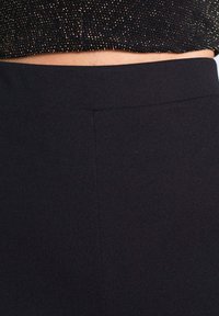 Jupe noire taille haute avec une texture de tissu lisse, des lignes épurées et un design simple. Pas de motifs visibles ni de détails en matériel.