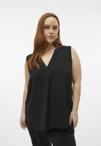Haut sans manches noir avec un décolleté en V, fabriqué en tissu texturé, présentant une coupe décontractée et des détails de couture subtils près du décolleté.