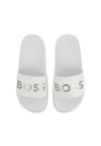 Witte slide sandalen met een gestructureerd oppervlak, voorzien van een brede band waarop het woord "BOSS" in metallic zilveren letters is afgebeeld.