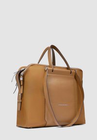 Bruine leren aktetas met dubbele handgrepen, een voorvak, zilverkleurige ritssluiting en een schouderriem op een lichtgrijze achtergrond.