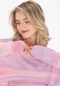 Weicher, gestrickter Pullover in rosa und lila Ombre, mit lockeren Ärmeln und lässigem Schnitt, der ein strukturiertes Garn und eine gemütliche Ästhetik betont.