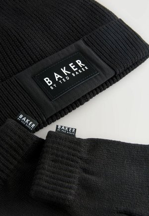 Bonnet en tricot noir et gants, tous deux étiquetés "BAKER par Ted Baker", présentés sur un fond clair. Accessoires d'hiver élégants.