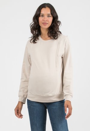 Beige maternity sweatshirt with a round neck, long sleeves, side panel detailing, and a relaxed fit, made from soft, stretchy fabric.