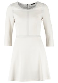 Robe blanche longueur genou avec manches trois-quarts, col rond, taille cintrée, tissu texturé et fermeture éclair au dos.