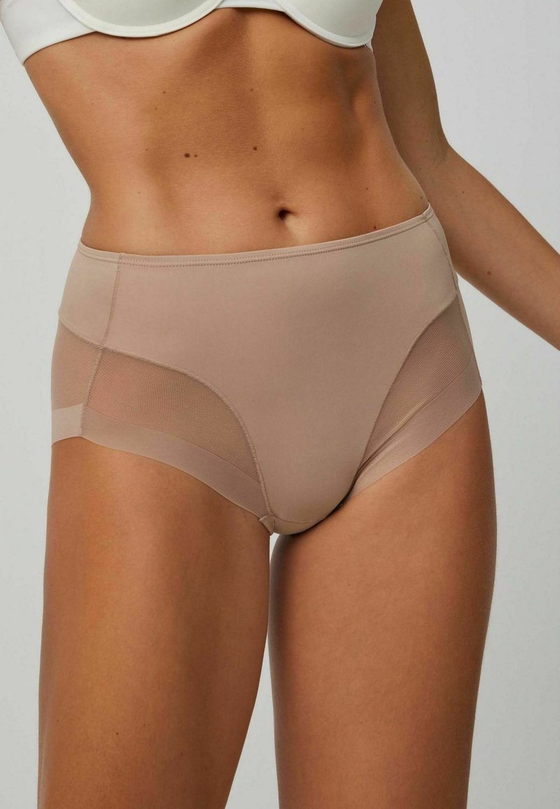 Bragas de talle alto en color beige, con un material suave y paneles de malla a los lados, además de una cinturilla sólida.