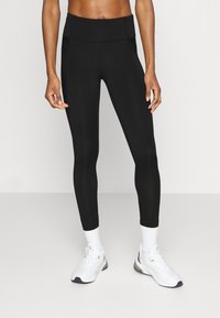 Černé legíny s vysokým pasem, vyrobené z elastického materiálu. Nosit s bílými sportovními botami a ponožkami. Čistý a jednoduchý design.