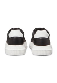 Schwarz-weiße Sneaker mit einem strukturierten schwarzen Mesh-Obermaterial, glatten schwarzen Lederelementen und einer klobigen weißen Gummisohle mit eingestanztem Logo.