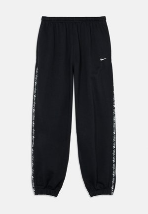 Pantalon de survêtement noir Nike avec taille et chevilles élastiques, logo Nike blanc sur la cuisse gauche et texte « Nike » répété le long des coutures latérales.
