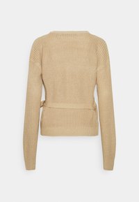 Beżowy sweter dzianinowy z długimi rękawami, okrągłym dekoltem i zawiązywanym paskiem w talii. Tekstura jest luźna i przewiewna.