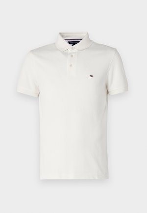 Polo din bumbac în culoarea albă murdară, cu guler clasic, plăcuță cu trei butoane și un mic logo brodat pe pieptul stâng.