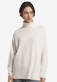 Cremefarbener Rollkragenpullover aus weichem Strickstoff mit gerippten Akzenten an Bündchen und Saum, mit legerer Passform und überschnittener Schulter.
